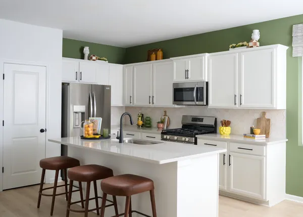a kitchen with stainless steel appliances a stove a sink a microwave a refrigerator and white cabinets