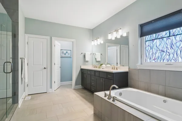 a bathroom with a tub a sink and mirror