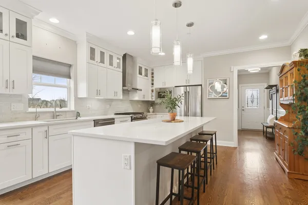 a kitchen with a sink a stove a refrigerator and white cabinets with wooden floor