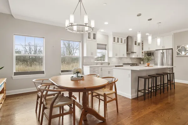 a dining room with stainless steel appliances a table chairs and chandelier