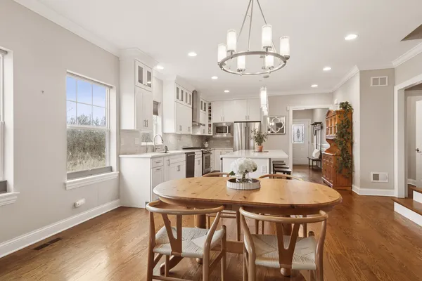 a view of a dining room and livingroom with furniture wooden floor a chandelier