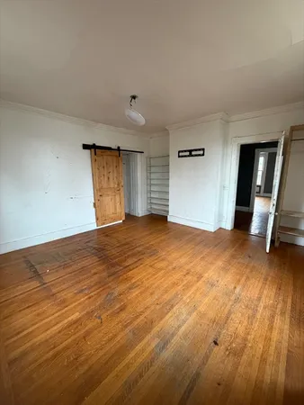 a view of empty room with wooden floor