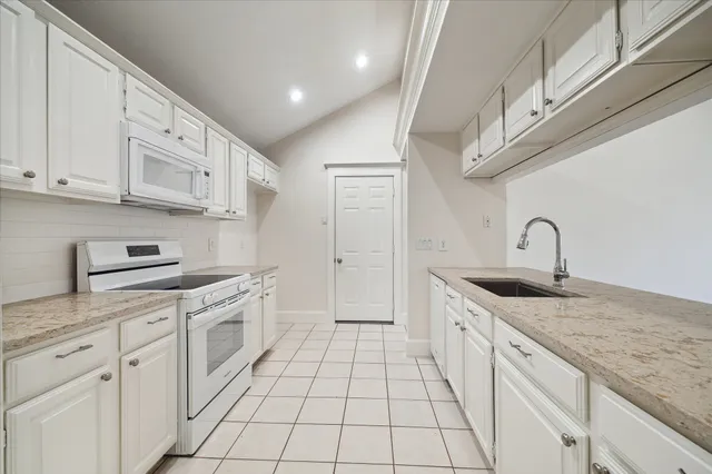 a large white kitchen with a sink and cabinets
