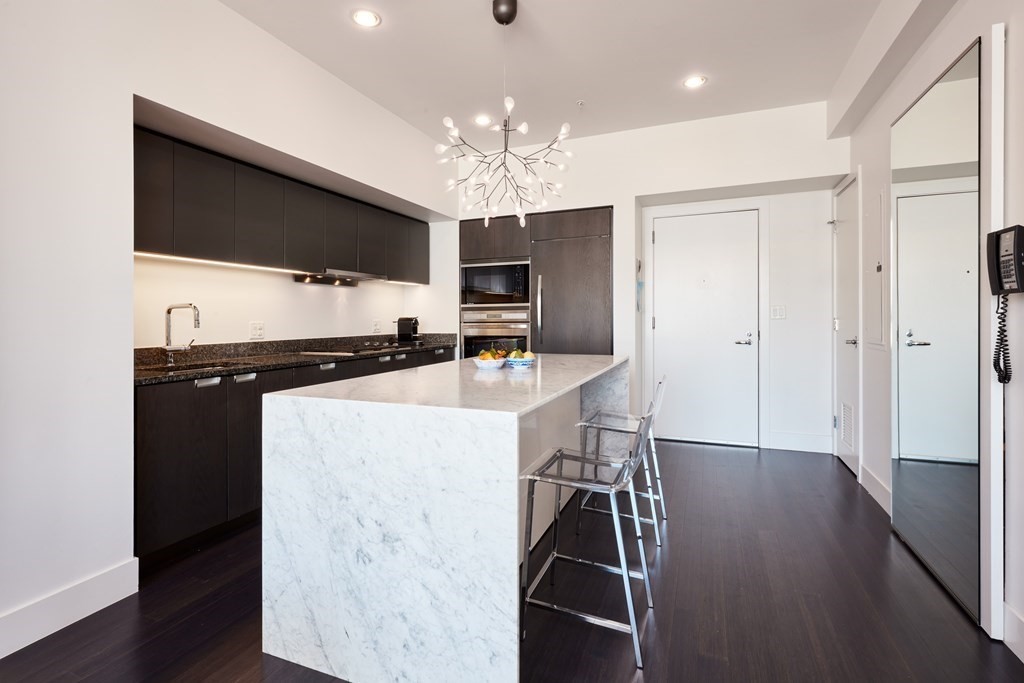 110 Stuart Street, Unit 26F Boston, MA 02116 - Photo 6 of 24 a kitchen with kitchen island a counter top space appliances and a ceiling fan