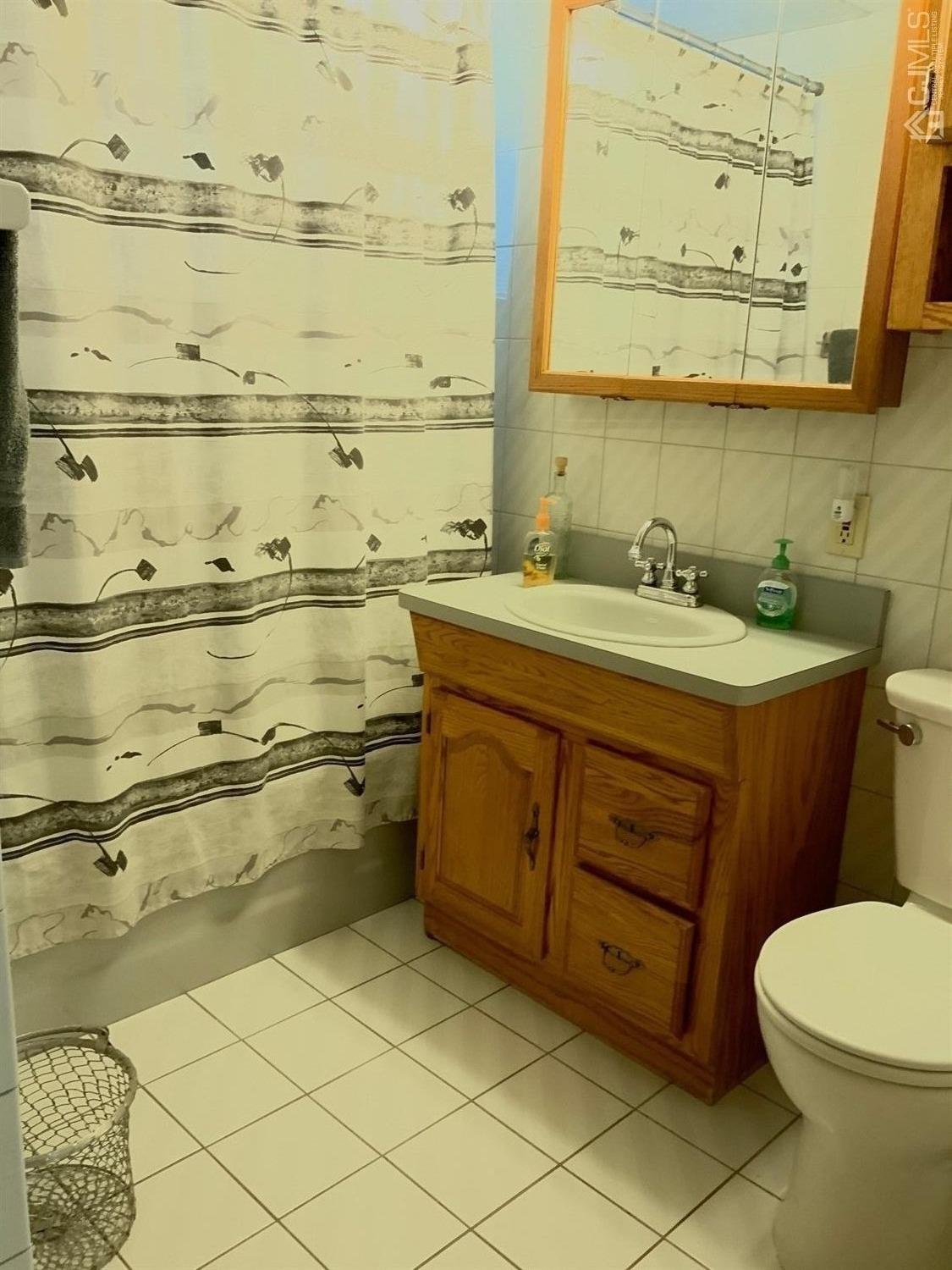 25 Penn Street Fords, NJ 08863 - Photo 16 of 20 a bathroom with a granite countertop sink a toilet and a mirror