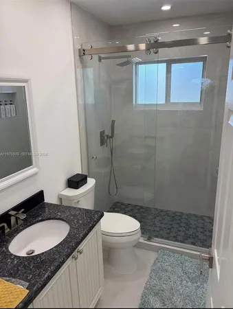 a bathroom with a granite countertop sink toilet mirror and shower