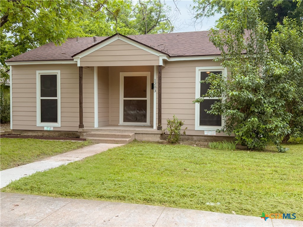 1203 South 5th Street Temple, TX 76504 - Photo 2 of 29 a white house that has a small yard and a large trees with wooden fence