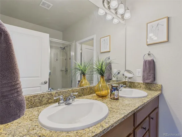 a bathroom with a granite countertop sink a mirror and a shower