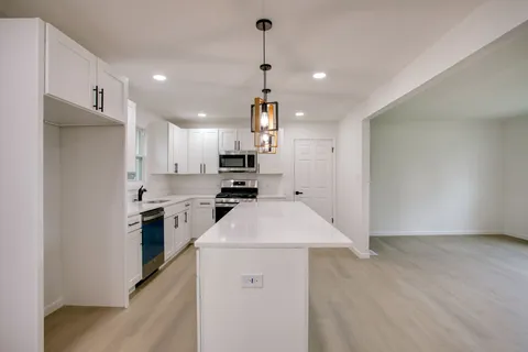 a kitchen that has a lot of white cabinets and stainless steel appliances