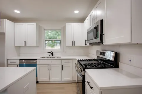 a kitchen with stainless steel appliances granite countertop a sink stove a refrigerator and white cabinets