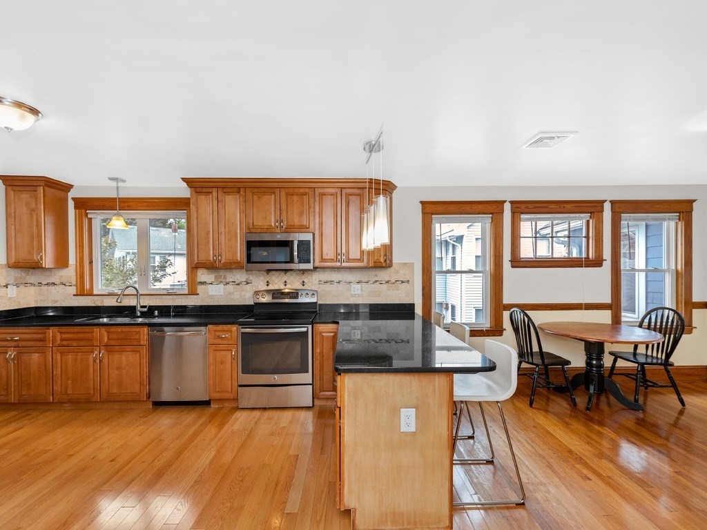 194 School Street, Unit 194 Watertown, MA 02472 - Photo 10 of 24 a kitchen with stainless steel appliances granite countertop a stove top oven a sink dishwasher a dining table and chairs with wooden floor
