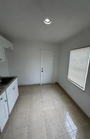a view of kitchen with refrigerator and white cabinets
