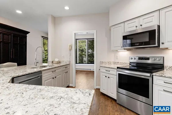 a kitchen with stainless steel appliances white cabinets a sink and a stove