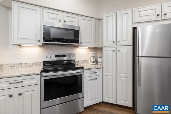 a kitchen with stainless steel appliances white cabinets white stove a microwave and a refrigerator