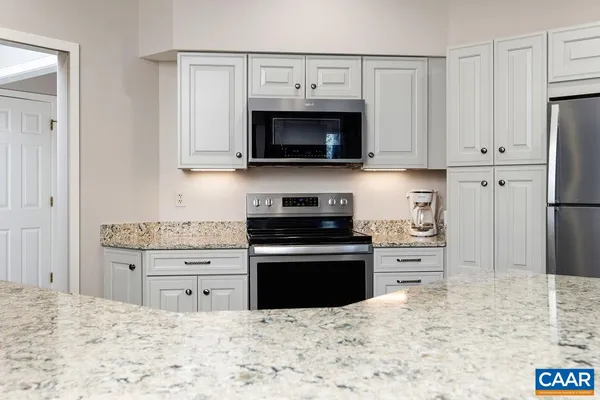 a kitchen with stainless steel appliances granite countertop a stove and a white cabinets