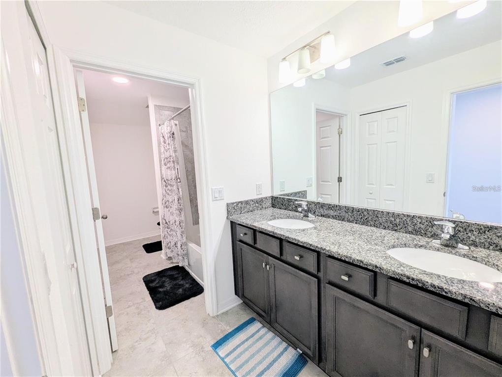 2944 Autumn Rock Drive Zephyrhills, FL 33540 - Photo 26 of 44 a bathroom with a granite countertop sink a toilet a mirror and shower