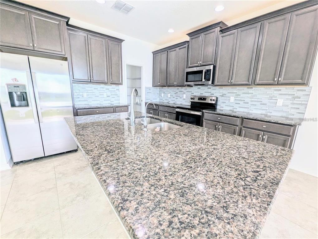 2944 Autumn Rock Drive Zephyrhills, FL 33540 - Photo 4 of 44 a kitchen with stainless steel appliances granite countertop a stove a sink and a microwave