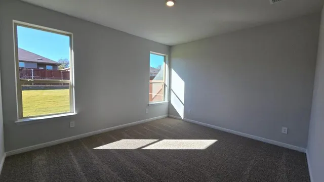 an empty room with chandelier fan and windows