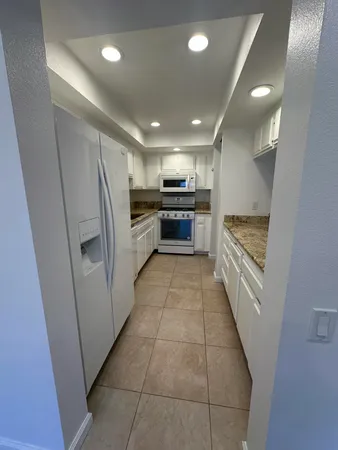 a large white kitchen with a stove a refrigerator a sink and dishwasher
