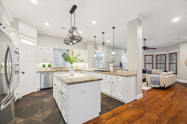 a kitchen with granite countertop a stove a sink a dining table and chairs with wooden floor