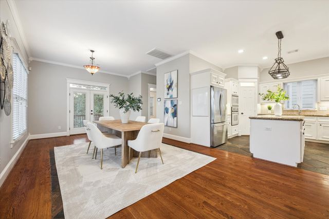 a kitchen with stainless steel appliances kitchen island granite countertop a table chairs in it and wooden floors