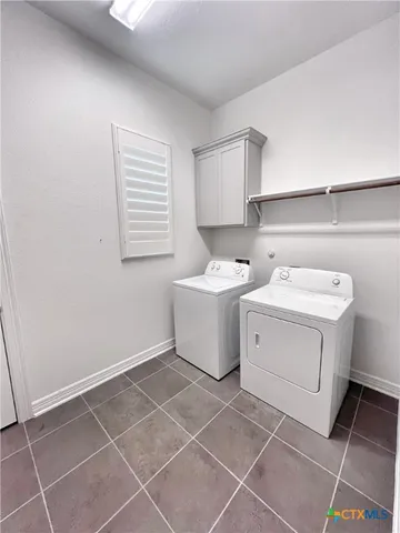 a utility room with a washer dryer and white cabinets