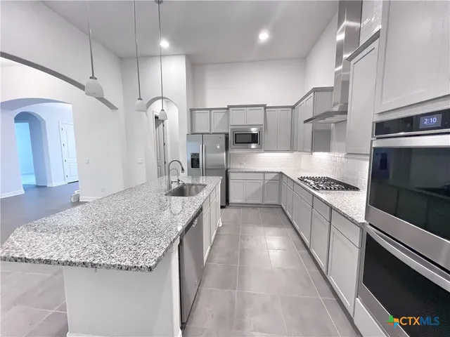 an empty room with chandelier fan and windows