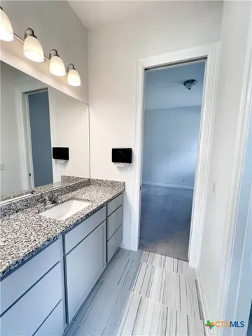 a bathroom with a granite countertop sink and a mirror