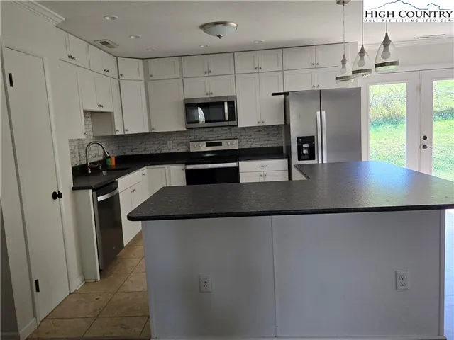 a kitchen with stainless steel appliances granite countertop a refrigerator a stove and a sink