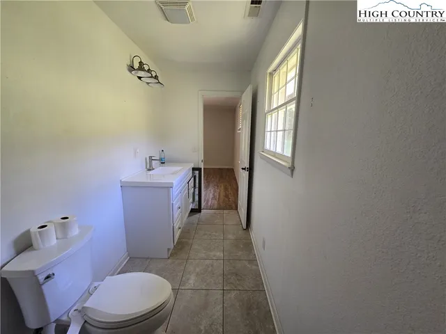 a bathroom with a sink a toilet a window and mirror