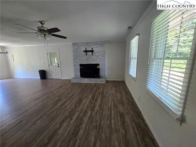 a view of a livingroom with wooden floor a ceiling fan and windows