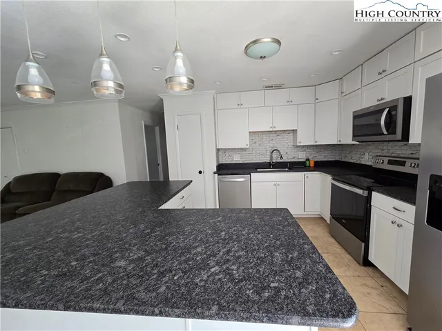 a kitchen with stainless steel appliances granite countertop a sink a stove top oven a counter space and cabinets