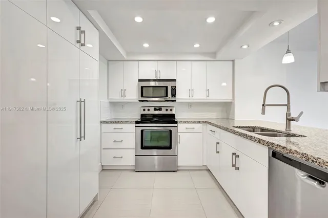 a kitchen with granite countertop white cabinets and stainless steel appliances