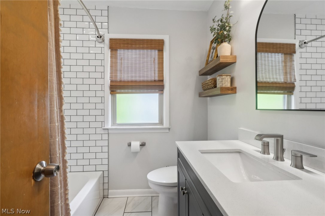 1389 Beaconfield Road Lyndhurst, OH 44124 - Photo 16 of 35 Full bathroom featuring vanity, a healthy amount of sunlight, shower / bath combination with curtain, toilet, and tile patterned flooring