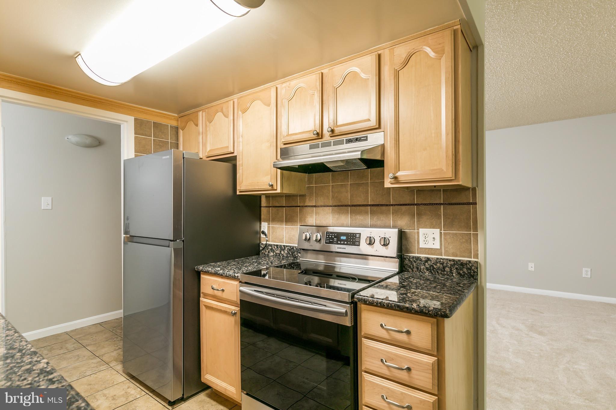 11650 Stoneview Square, Unit 11C Reston, VA 20191 - Photo 4 of 26 a kitchen with stainless steel appliances granite countertop a stove a refrigerator and a cabinets