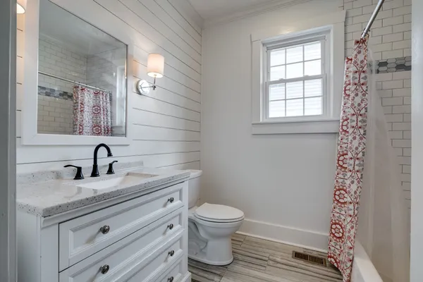 a bathroom with a granite countertop sink toilet a mirror and shower