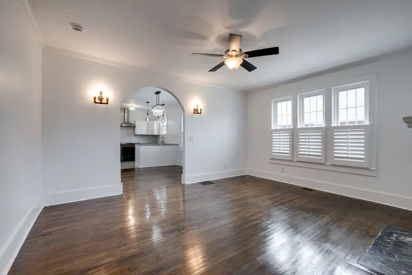 a view of a livingroom with a chandelier fan and wooden floor