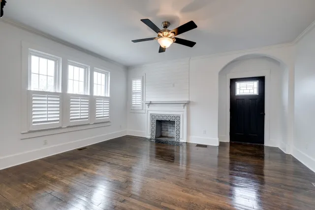 an empty room with wooden floor a ceiling fan and windows