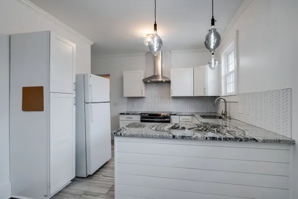 a kitchen with stainless steel appliances granite countertop a refrigerator a stove a sink and white cabinets