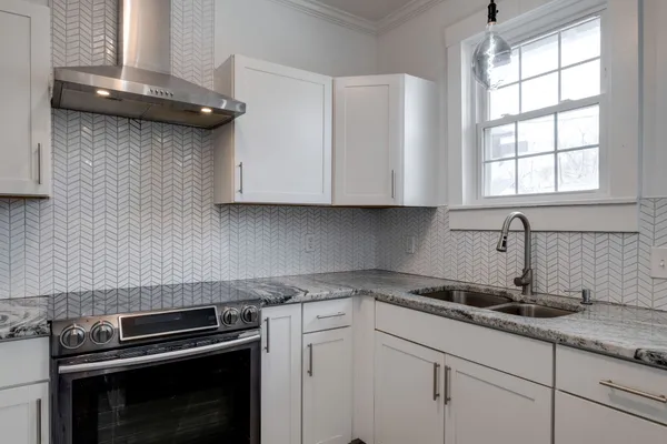 a kitchen with granite countertop white cabinets and a stove