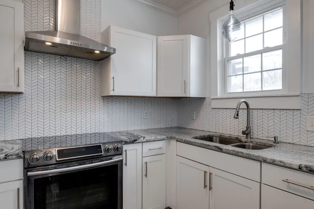 a kitchen with granite countertop white cabinets and a stove