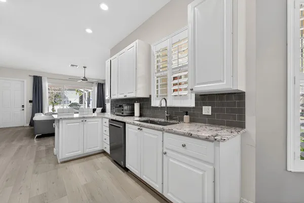 a kitchen with a sink white cabinets and white appliances
