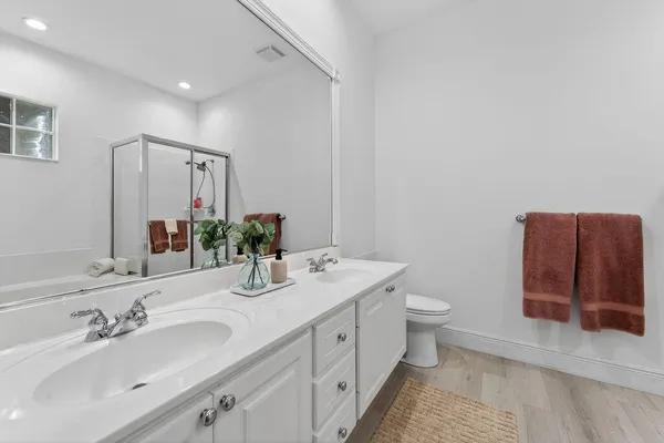 a bathroom with a double vanity sink toilet and mirror