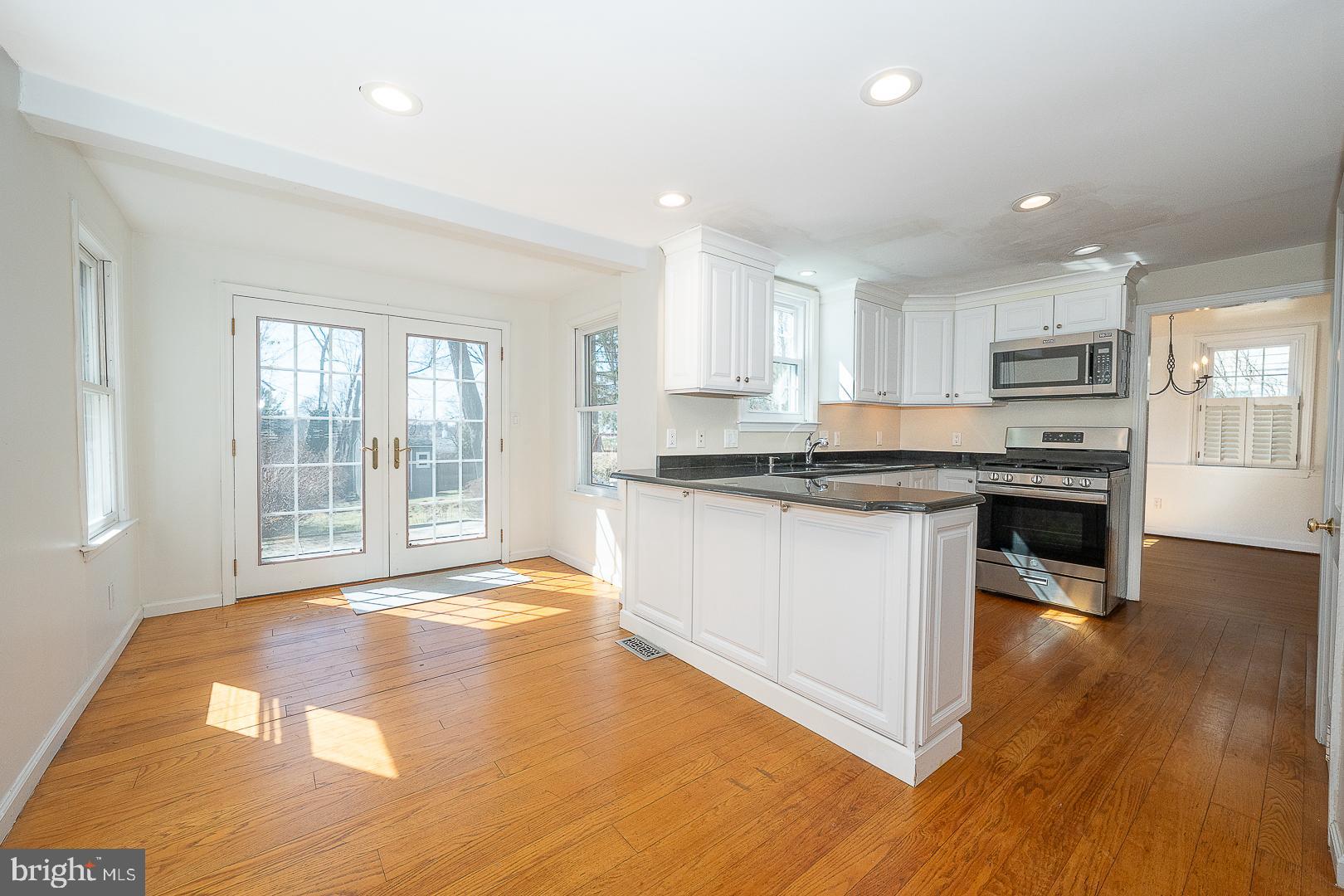 128 Homestead Road Wayne, PA 19087 - Photo 9 of 30 a kitchen with granite countertop a stove a sink a refrigerator and white cabinets with wooden floor