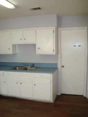 a kitchen with granite countertop white cabinets and a wooden floor
