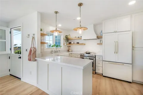 a kitchen with stainless steel appliances granite countertop a sink a stove a refrigerator and island with wooden floor