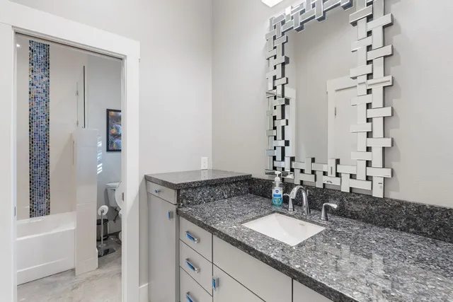 a bathroom with a granite countertop sink and a mirror