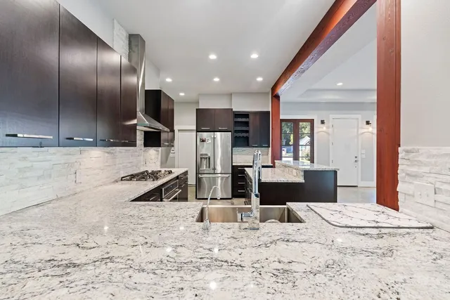 a kitchen with stainless steel appliances kitchen island granite countertop a refrigerator and a sink