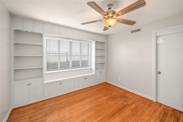 a view of an empty room with a window and a ceiling fan