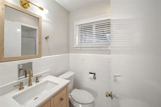 a bathroom with a sink vanity mirror and toilet